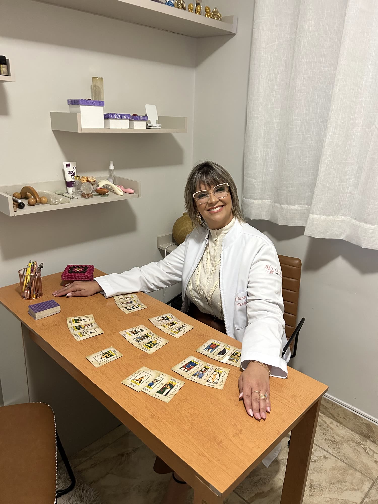 Juliana sorrindo com cartas de tarô na mesa